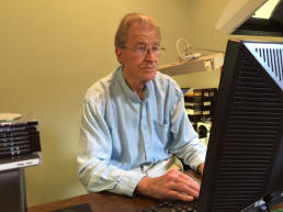 Picture of Ed at his desk, busy on the phone